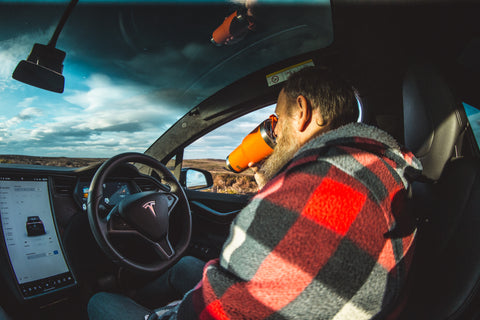 Man drinking from a tumbler in a car